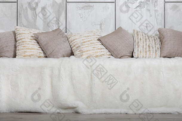 沙发上放着许多枕头，在大理石墙的背景下，沙发上覆盖着一层巨大的毛绒面纱。