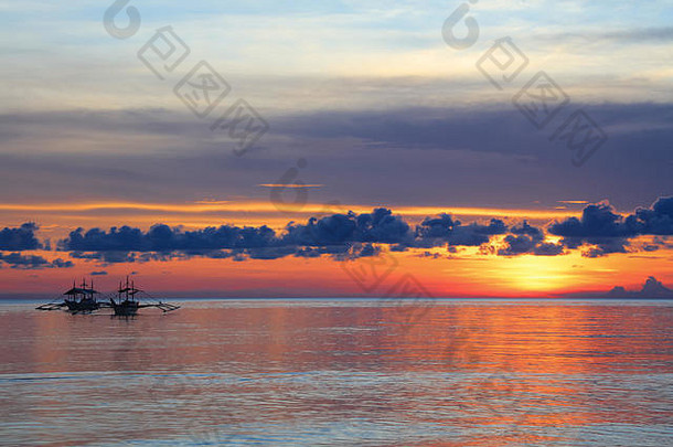 菲律宾长滩岛迪尼维德海滩日落时的两艘渔船