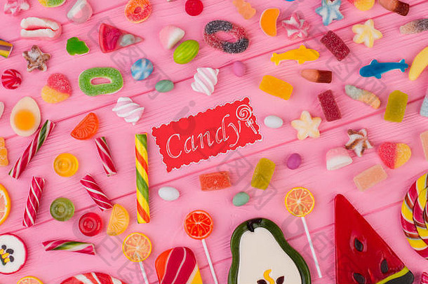 粉红色背景上有不同形状的彩色糖果。