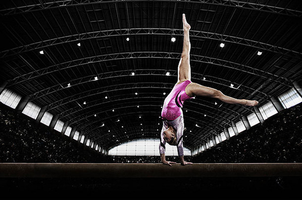 在横梁上表演的年轻女子体操运动员，双手在一个狭窄的器械上保持平衡。