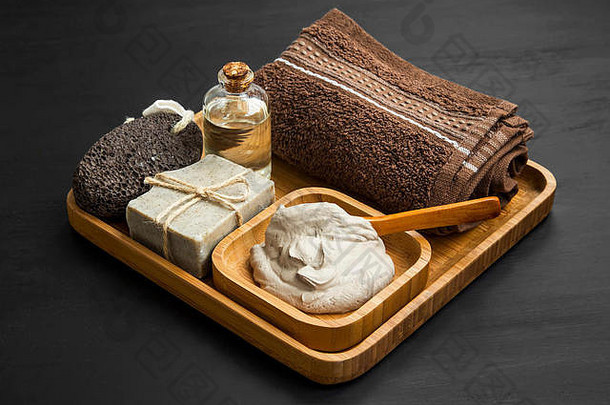 木制竹托盘中的粘土面膜、天然肥皂、软毛巾和面霜护肤spa