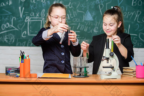 激励小女孩们拿着显微镜。生物实验室，快乐的天才。小女孩在学校实验室里是天才。科学实验室。实验室里的科学实验。实验室化学研究。