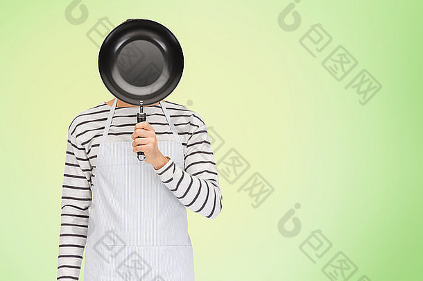 围裙里的男人或厨师把脸藏在煎锅后面