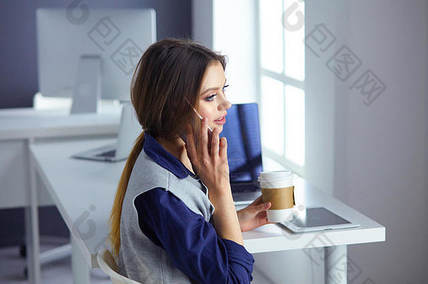 戴着耳机的专注专注的女人坐在桌旁，拿着笔记本电脑，看着屏幕，做笔记，在互联网上学习外语