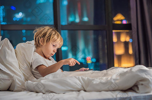 男孩平板电脑床上睡眠背景晚上城市孩子们技术概念
