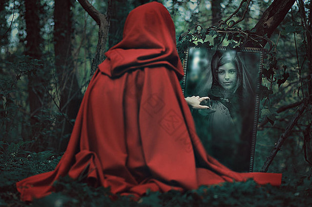 神秘的红帽女人站在一面<strong>魔镜</strong>前。黑暗幻想