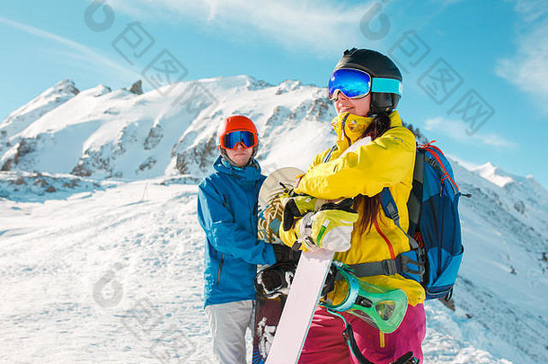照片运动型男人。女人滑雪板背景雪山