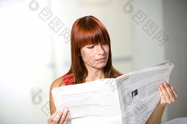 在办公室里看报纸的女人。