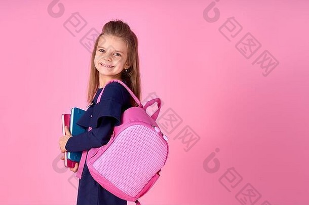 回到学校的概念半<strong>翻照片</strong>肖像可爱自信美丽聪明的女孩与抄写本笔记本穿着校服礼服粉红色明亮的背包。