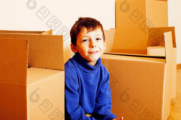 可爱的小男孩在空荡荡的房间里，带着许多盒子，搬到了新家