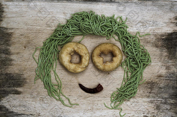 木质背景上的笑脸，由蔬菜和面条制成，并为文本留出空间。