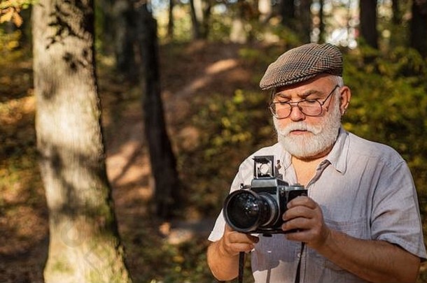 旅行拍摄。森林里的摄影师。秋天自然的生活方式。复<strong>古摄影</strong>设备。有胡子的成熟男人。拍摄绿色景观。摄影师正在拍照。风景摄影。