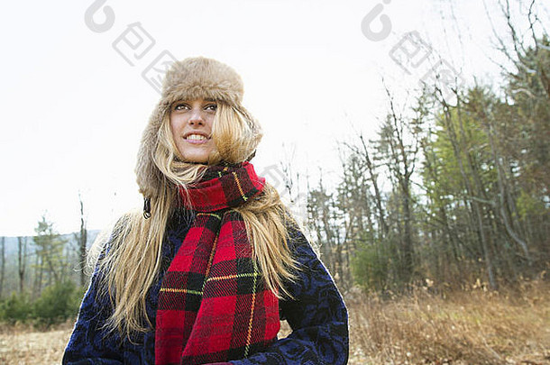 冬天，一个戴着温暖的毛茸茸的帽子和一条红色格子呢大围巾的女人在户外