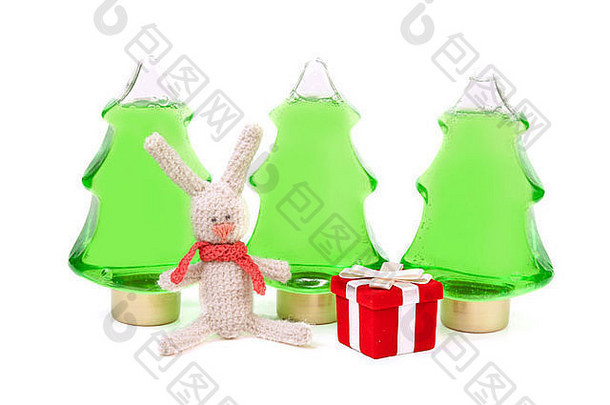 编织的兔子和一个红色的盒子，背景是三个绿色的瓶子，形状像圣诞树
