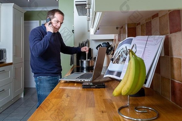 在CVID-19冠状病毒大流行隔离封锁期间压力下在家工作的悲惨男子在厨房工作