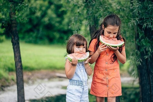 两个快乐的姐妹在春天公园户外吃西瓜