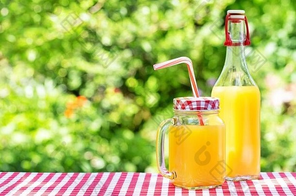<strong>柳橙汁</strong>装在梅森罐子里，装在木桌上的瓶子里