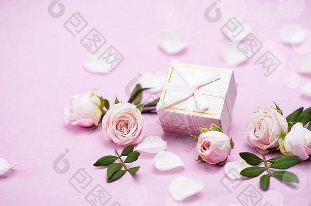 粉红背景上的玫瑰花蕾、花瓣、礼品盒。贺卡的概念。婚礼、情人节、生日