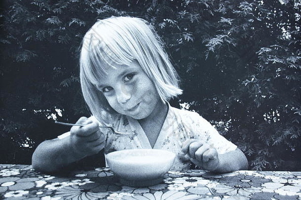 20世纪70年代拍摄的一个白人女孩吃一碗麦片的黑白艺术摄影。