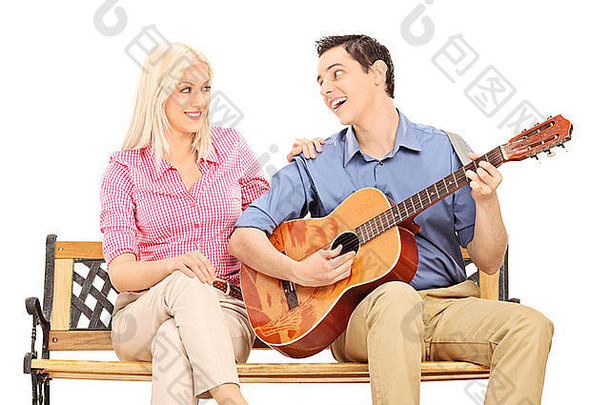 为坐在长凳上的女孩弹吉他的男人