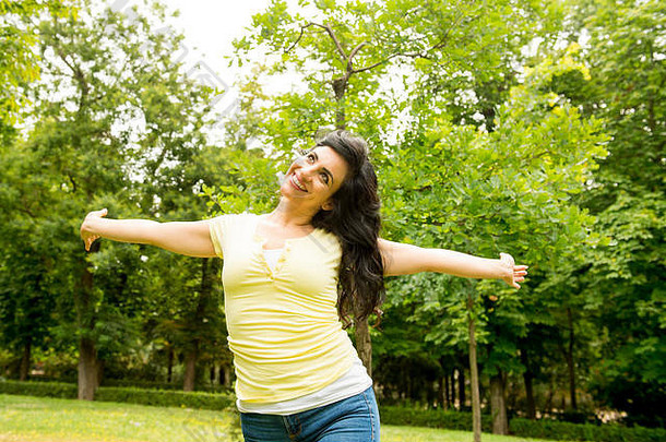 快乐有吸引力的拉丁女人扔手空气放松绿色郁郁葱葱的公园梅多斯