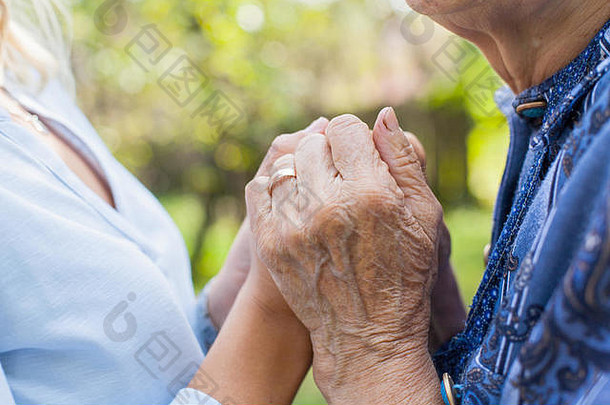 焦急的老妇人握着年轻女子的手的特写镜头