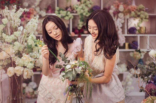美丽的亚洲女花匠们在花店里愉快地工作着，那里有很多春天的鲜花