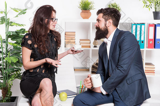 边喝茶边讨论。在工作休息期间参加商务讨论的专业夫妇。商务人士在办公桌旁放松和交流。关于业务的讨论。
