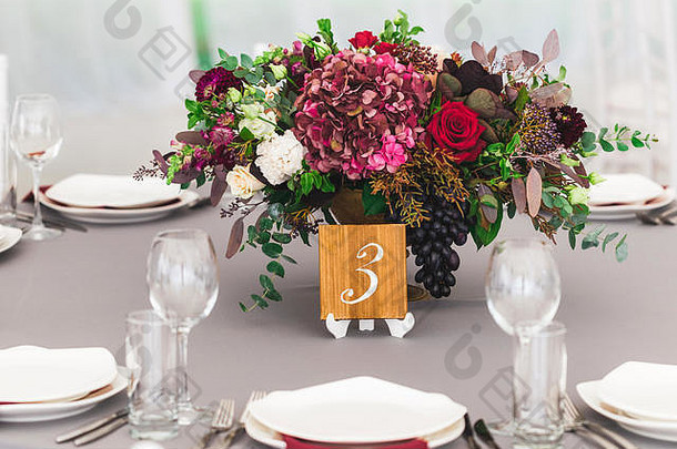 美丽的红色花束，绣球花放在婚宴桌上，木制盘子上有<strong>桌号</strong>