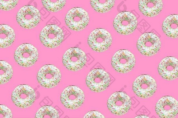 由白色釉面的环形甜甜圈和粉红色背景上的成百上千个甜甜圈组成的图案
