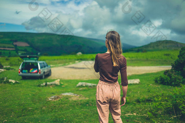 一位年轻女子停车后在大自然中行走