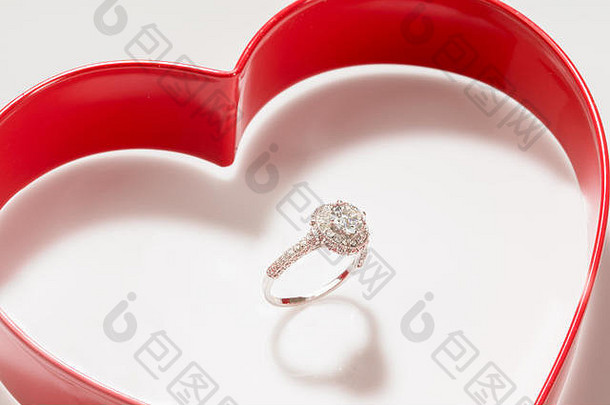 钻石戒指镶嵌在白色背景的红心盒内