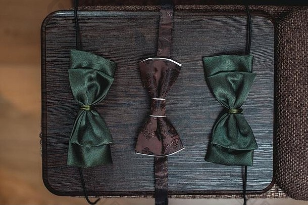 三个棕色和深绿色系在木板上的蝴蝶结