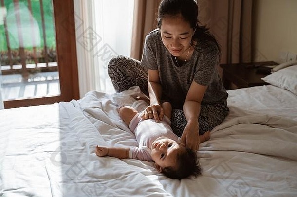 妈妈牵着小女儿的手在床上开玩笑