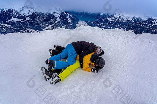 在一场胜利的比赛后，年轻人躺在雪地上堆成一堆，站在全景山前。
