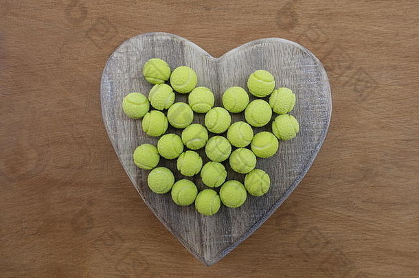 黄色的网球在木制的心形上甜甜的