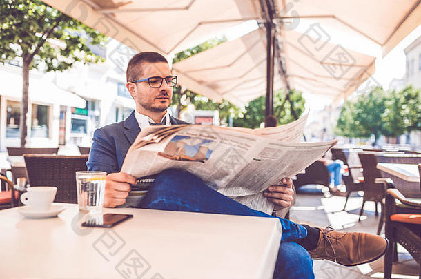 一位戴眼镜坐在咖啡馆看报纸的年轻商人的画像