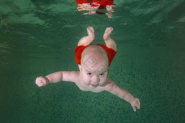 小学会在水下游泳。婴儿在蓝色背景<strong>的</strong>游泳池里游泳。健康<strong>的</strong>家庭生活方式和儿童