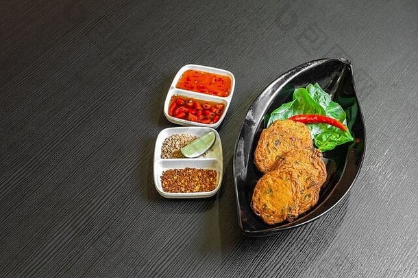 香辣炸鱼饼（Tod Mun Pla），一种传统的泰国开胃菜，由新鲜鱼酱、长豆、红咖喱酱和卡菲尔莱姆叶制成