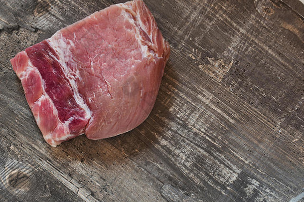 平铺的生猪肉牛排。新鲜生肉放在木桌上。猪排未煮熟，未切割，可随时烧烤。