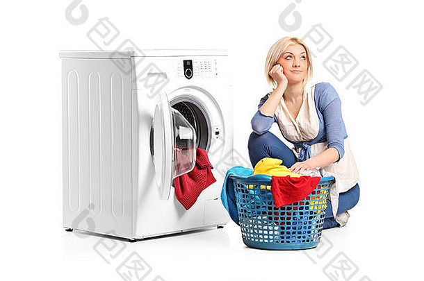一位年轻女子坐在洗衣机旁，想着衣服
