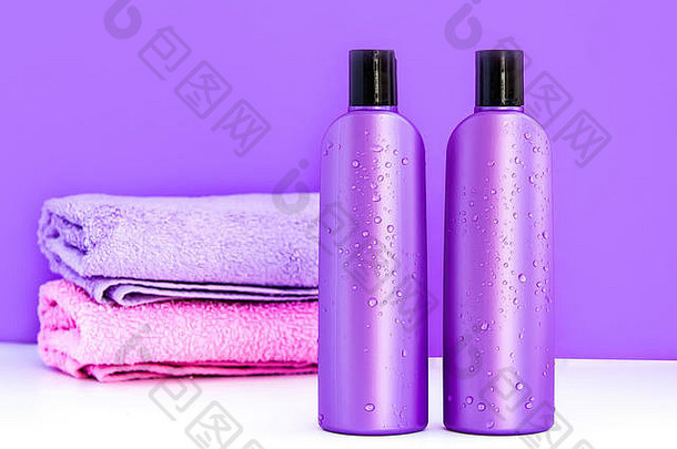 两个紫色化妆瓶和两条浴巾，用于水疗、身体和头发护理