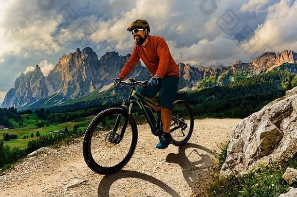 游客在Cortina d'Ampezzo骑自行车，背景是令人惊叹的落基山脉。人骑MTB耐力流径。意大利南蒂罗尔省，多尔
