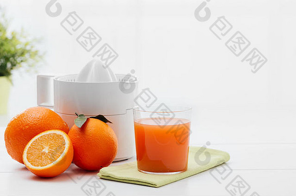 健康新鲜的果汁，榨汁机和橙子放在厨房的桌子上