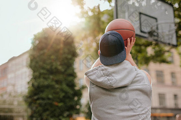 街球运动员投篮的后视图。一个夏天在户外球场打篮球的年轻人。