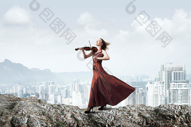 女人小提琴家红色的衣服玩旋律多云的天空