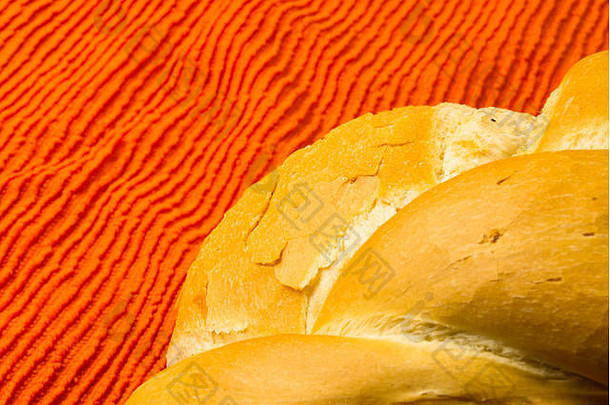新鲜的白色小麦编织面包，放在橙色餐巾上