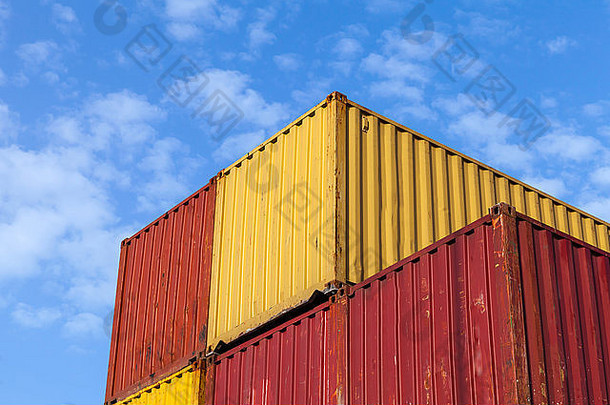 五颜六色的金属工业货柜堆在蓝色多云的天空下