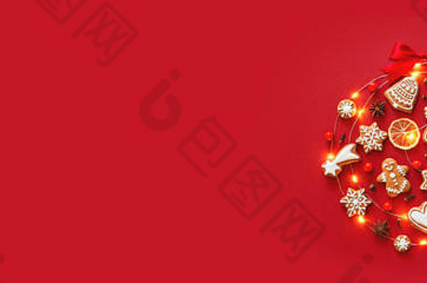 创意圣诞球由冰姜饼饼干、八角星、浆果、橘子片、红色背景上装饰的红丝带蝴蝶结制成。<strong>新年横</strong>幅。顶视图。