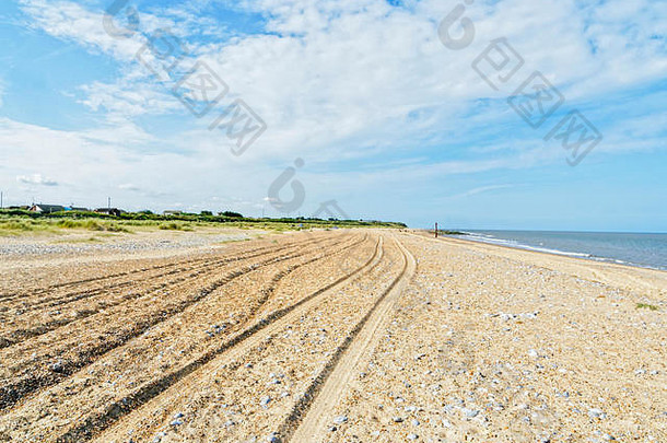 在英格兰诺福克市凯斯特海边的一个空海滩上，一组深深的轮胎痕迹一直延伸到远处。